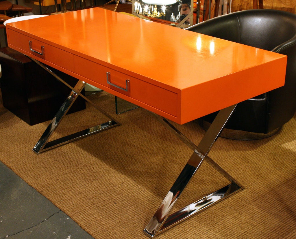 A chic vibrant orange lacquered campaign desk with two drawers, raised on X form polished chrome plated steel legs. By Milo Baughman. American, circa 1975.

Please call gallery for details, availability and item location.