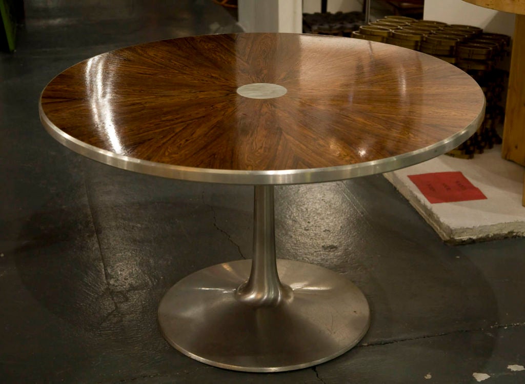 A beautiful game, dining, or center table with a rosewood sequence matched veneer top in a radiating pattern around an inlaid aluminum circle, with a aluminum trim and aluminum pedestal extending into a round base. By Steen Ostergaard for CADO.