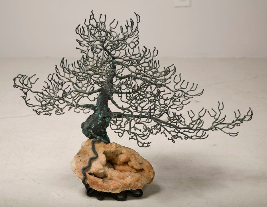 An exotic bonsai tree sculpture in bronze mounted on a champagne colored geode, with tree roots crawling around its surface then trailing down to create a multi-footed support. By Curtis Jere. American, circa 1970