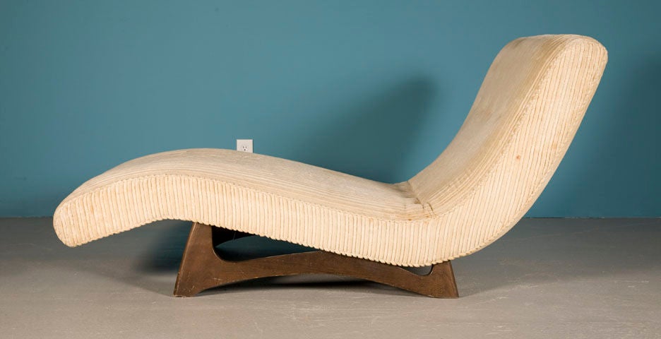 A low and wide chaise longue in a wave form raised on sculpted wood legs. By Adrian Pearsall for Craft Associates. U.S.A., circa 1950.