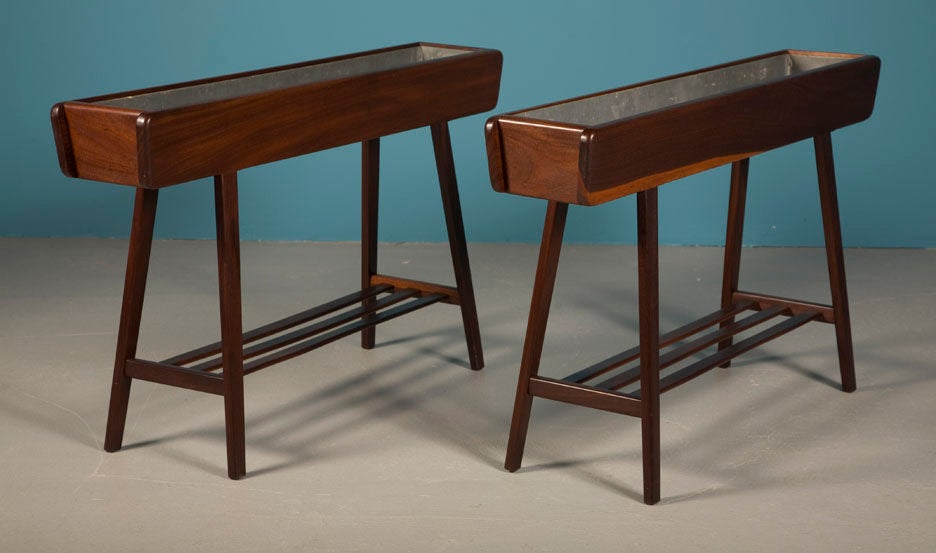 A pair of jardinière stands comprising a walnut cased top in a rectangular box with galvanized steel liners supported by four square tapered walnut legs with a three slat stretcher, which can serve as a lower shelf. Denmark, circa 1950.