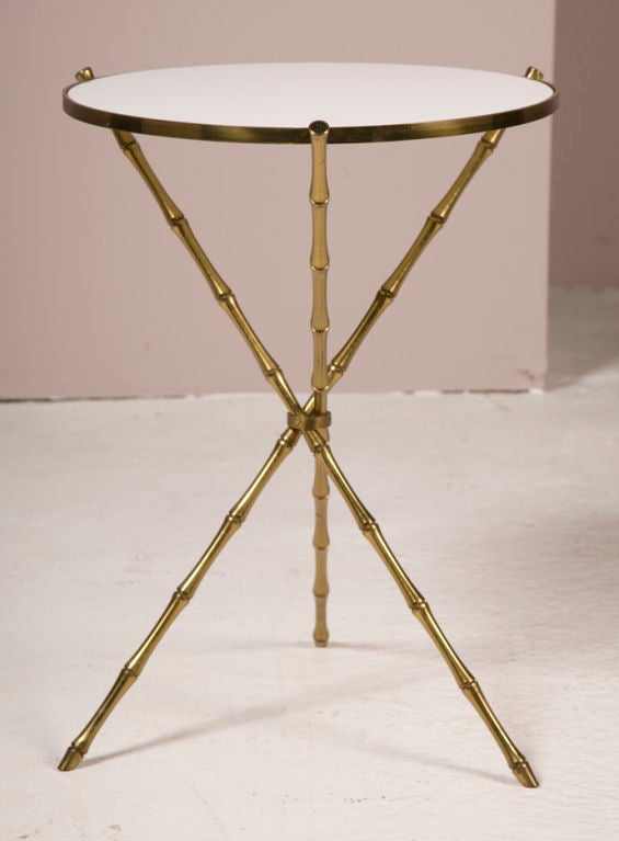A faux bamboo tripod table in brass with a white Vitrolite glass top after Bagues. Italian, circa 1960.