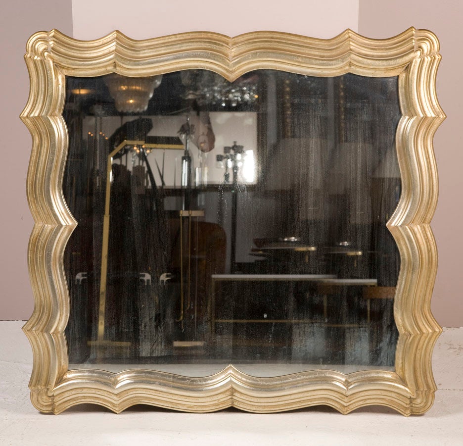 A large carved wood frame mirror with silver leaf and antiqued mirror by Dorothy Draper. American, circa 1940.