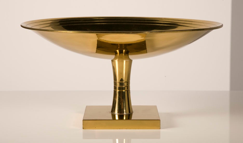 A fine polished brass footed compote consisting of a shallow circular bowl with three incised concentric rings and a delicate lip raised on a concave round stem and square base designed by Tommi Parzinger for Dorlyn. Stamped with maker’s mark at the