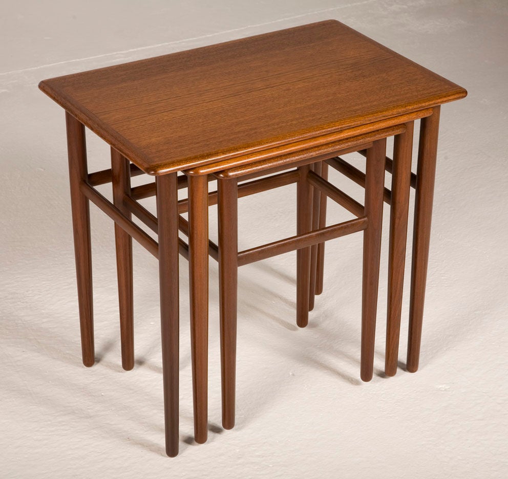 A beautiful set of three nesting tables in teak, each with bull-nose edges and round tapering legs, two with three stretchers the smallest with four stretchers. Denmark, circa 1950.