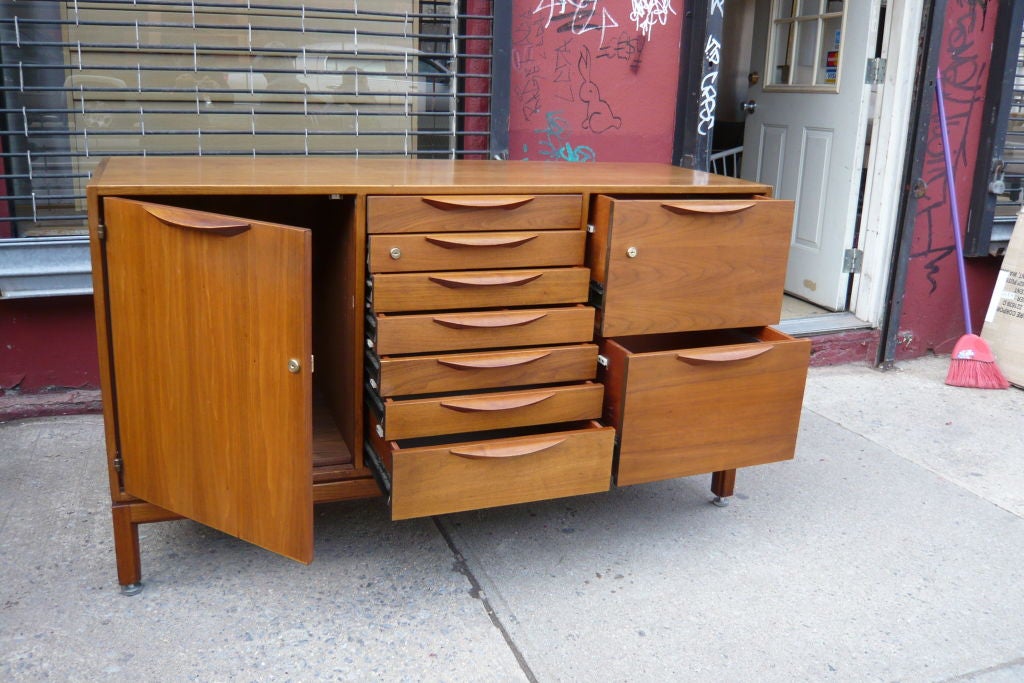 Jens Risom for Risom designs ca.1965 Walnut file credenza with solid Walnut sculpted  handles in near mint condition.7 drawer center bank is flanked by a full height door with adjustable shelf interior on left and 2 full depth file drawers on right