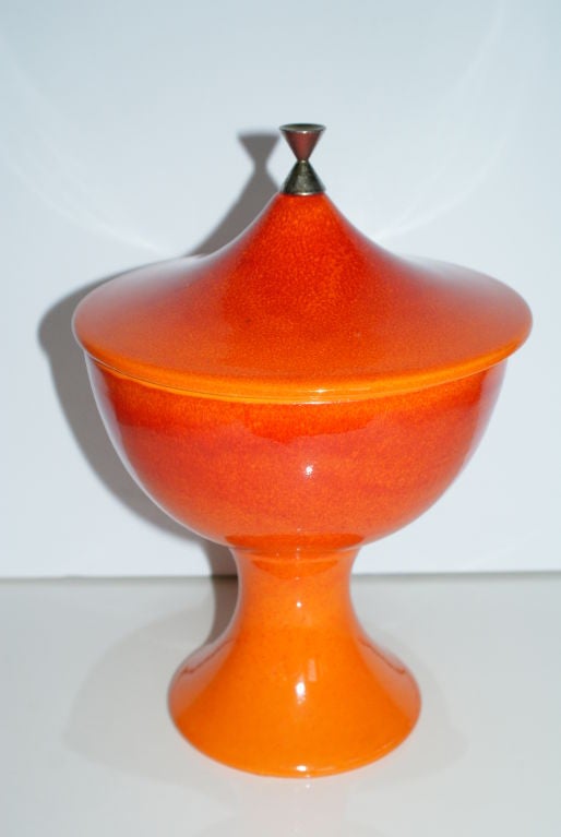 Tall bright orange pedestal bowl with removable lid and brass finial.
