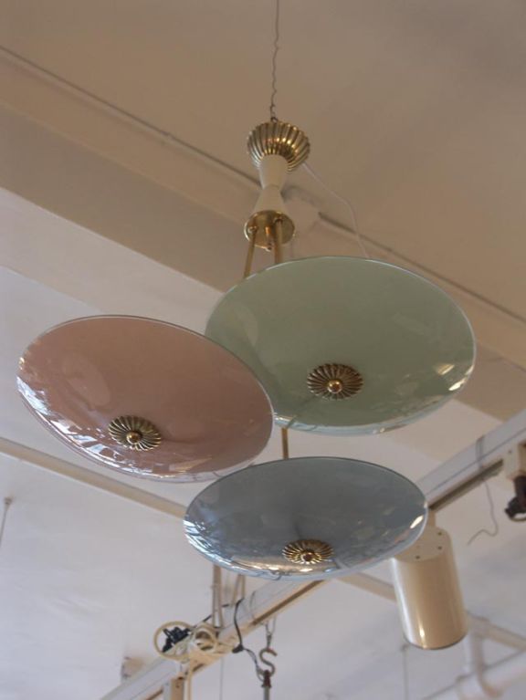A group of 3 pastel glass shades, one each red, blue, green, are suspended on an ornate brass fixture. Each shade is held by a brass floral finial, which matches the brass canopy. The glass may of course be arranged in any order. A group of 2 are