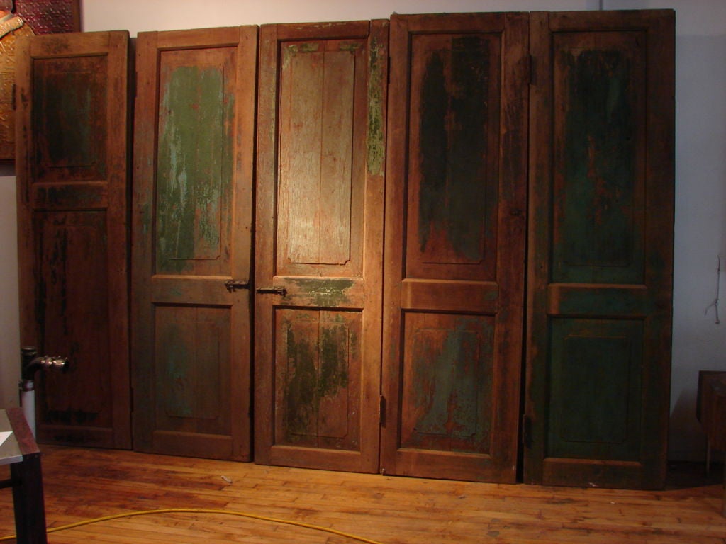 A beautiful set of antique teak wood doors from a food shop. These were originally used to shutter the store when it was closed at nite. Traces of green and pale blue paint remain in places. sold as a set of five doors. priced as a set. Can be