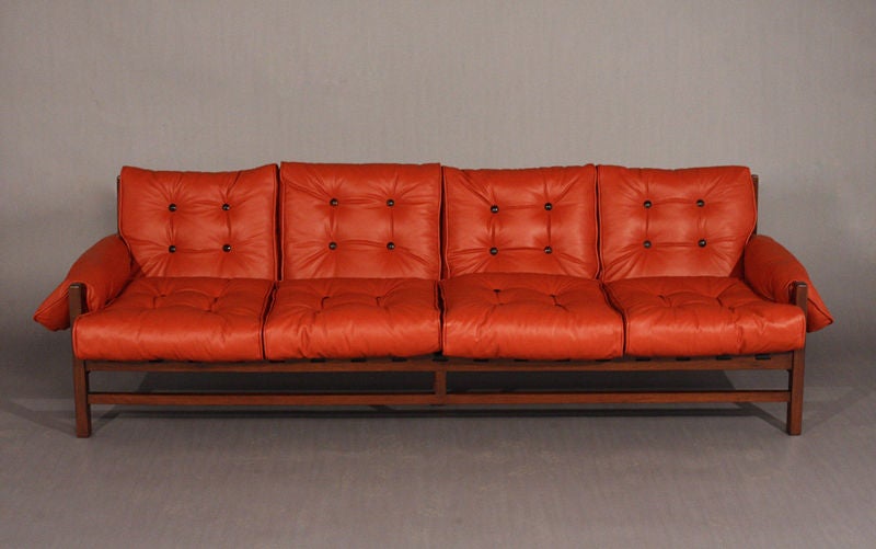 The rosewood frame sofa has red leather cushions that wrap around the arms and black pigskin straps that support the back and seat.  See also separate listing with matching pair of chairs.

Many pieces are stored in our warehouse, so please give
