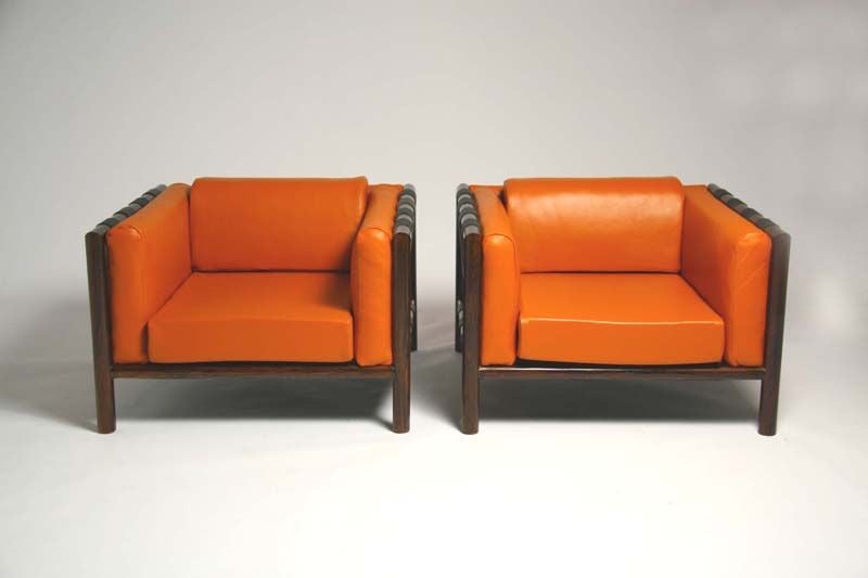 Pair of rosewood and orange leather arm chairs