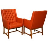 A pair of high tufted leather and teak arm chairs