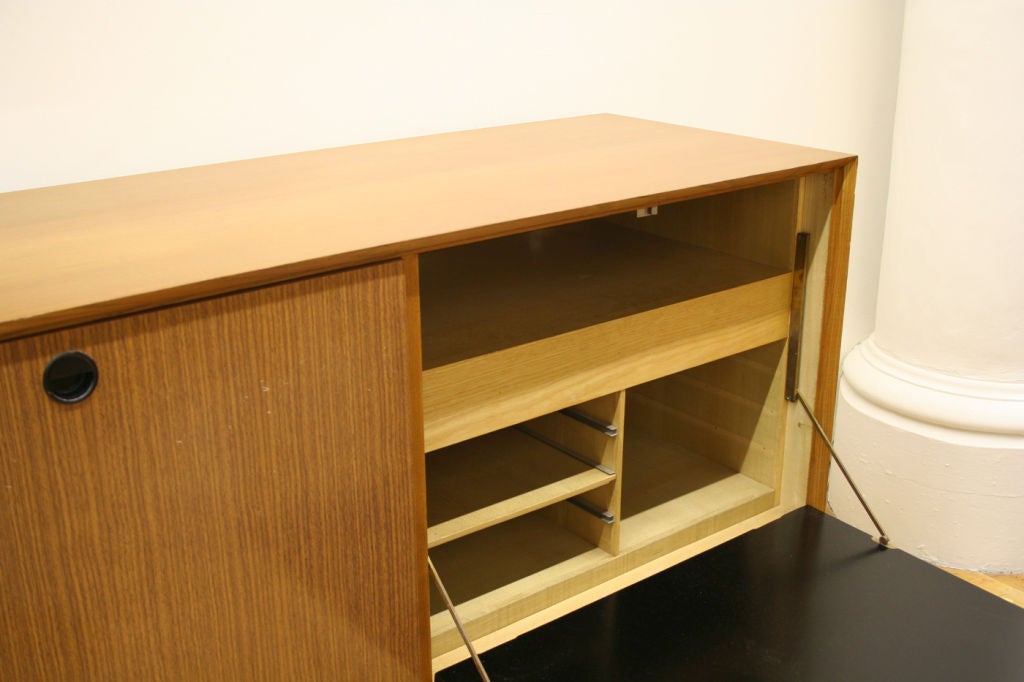 Cabinet with four drop down doors that open to reveal inner shelves al sit son top of two enameled bow tie shaped legs