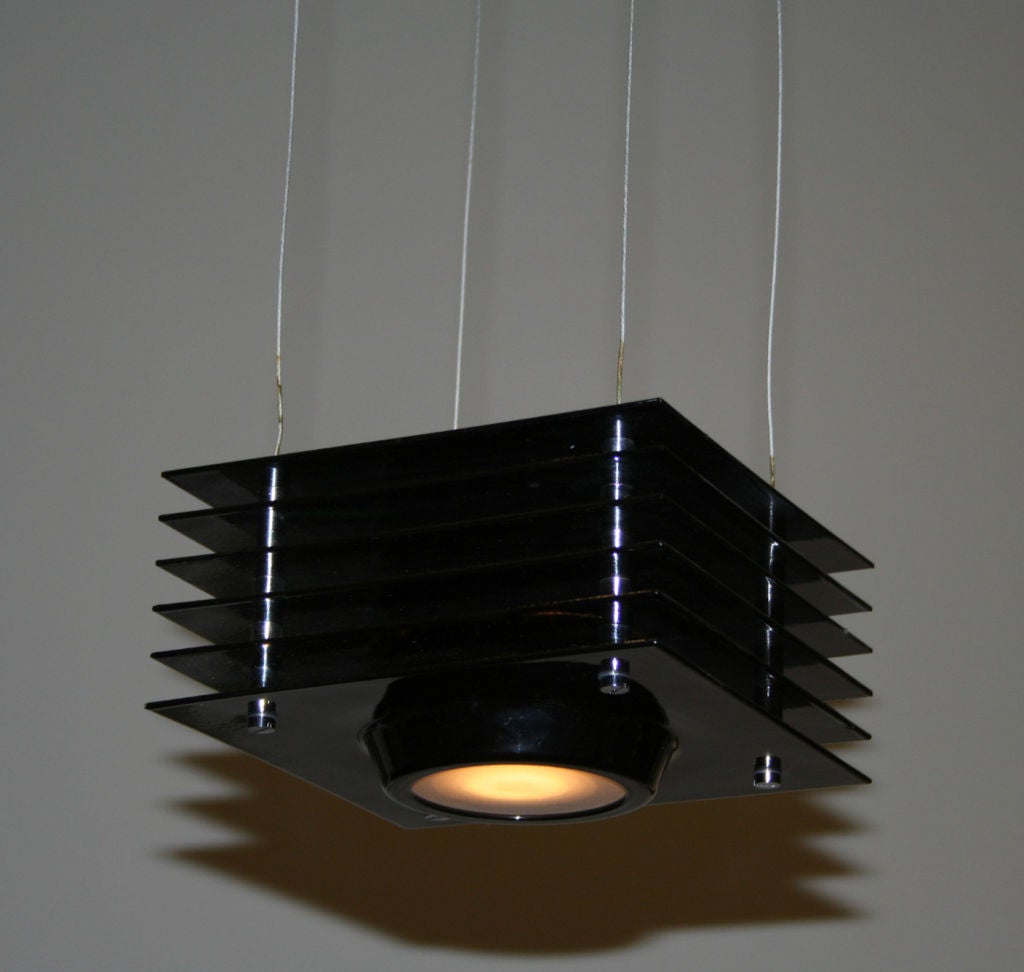 Hanging light black laquare metal, with a square light housing and circular aperture set with frosted glass, hung from four thin wires and a square electrical box
