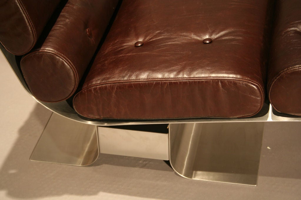 Pir of lounge chairs in stainless steel with pieced leather seat and back cushions that attach through frame.