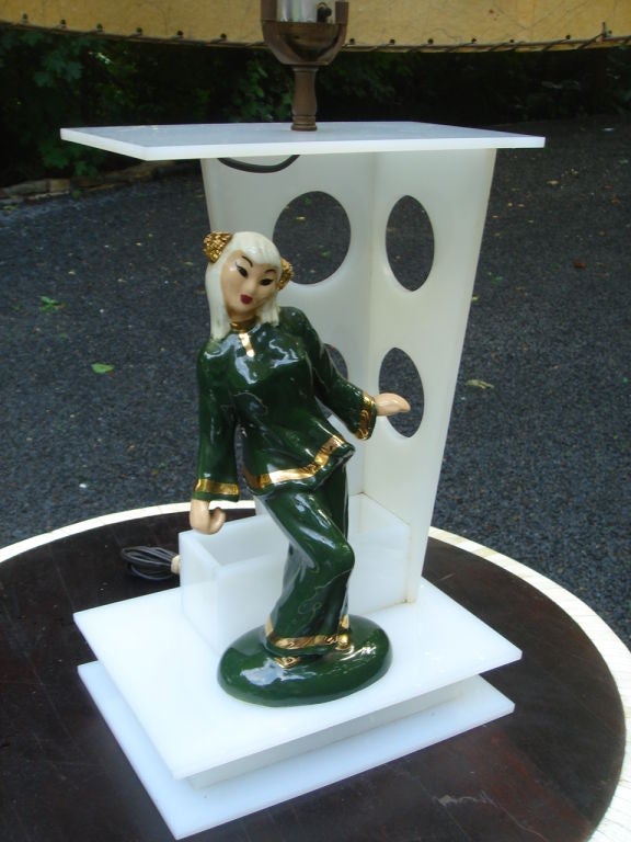 A Moss table lamp, white plexiglass with hand-painted ceramic Hedi Schoop Asian style figure, period vintage shade. Base is illuminated. Figurine signed. <br />
Shade- 17 diameter x 9.5
