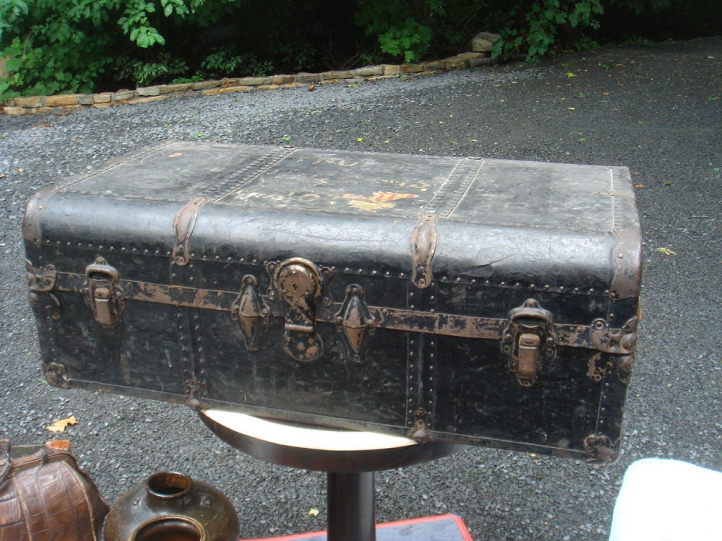 A classic steamer trunk, wood clad in metal with leather straps at either end and riveted banding. Excellent height to serve as a coffee table suitcase. No key for the latch, although presently open.<br />
A great piece of luggage.<br