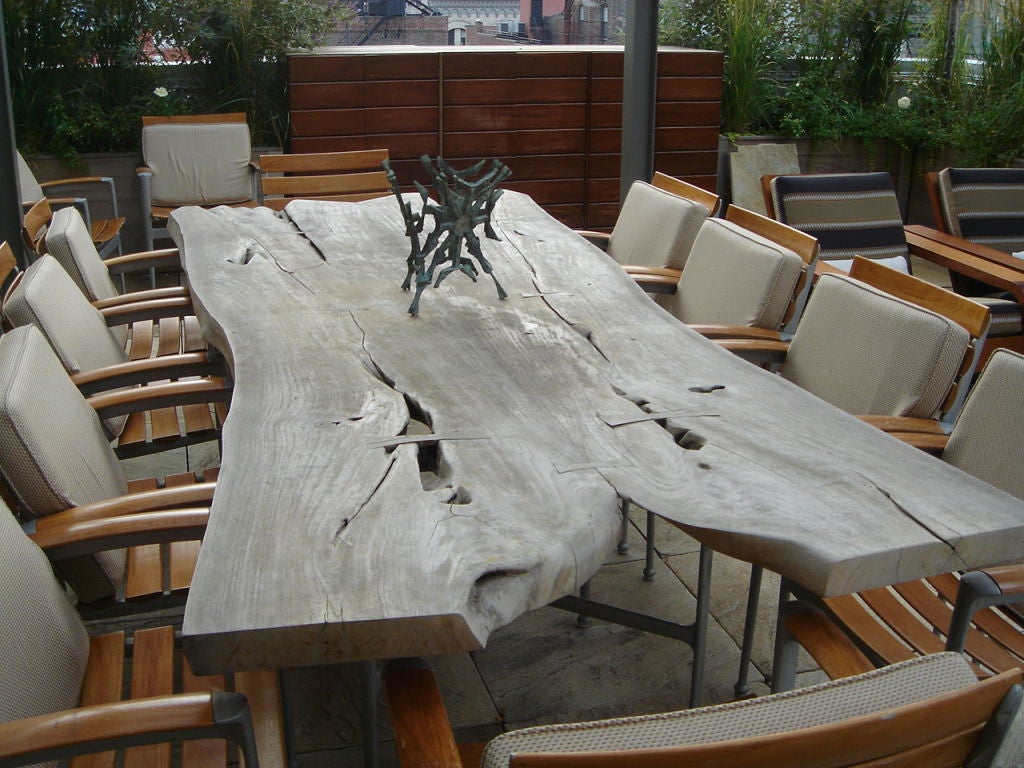 A private commission free form monumental table with cast aluminum base and matching Caldwell chairs. The table will stain to a honey color if stained (this one has been left to fade outdoors). A picture has been included that shows the color when