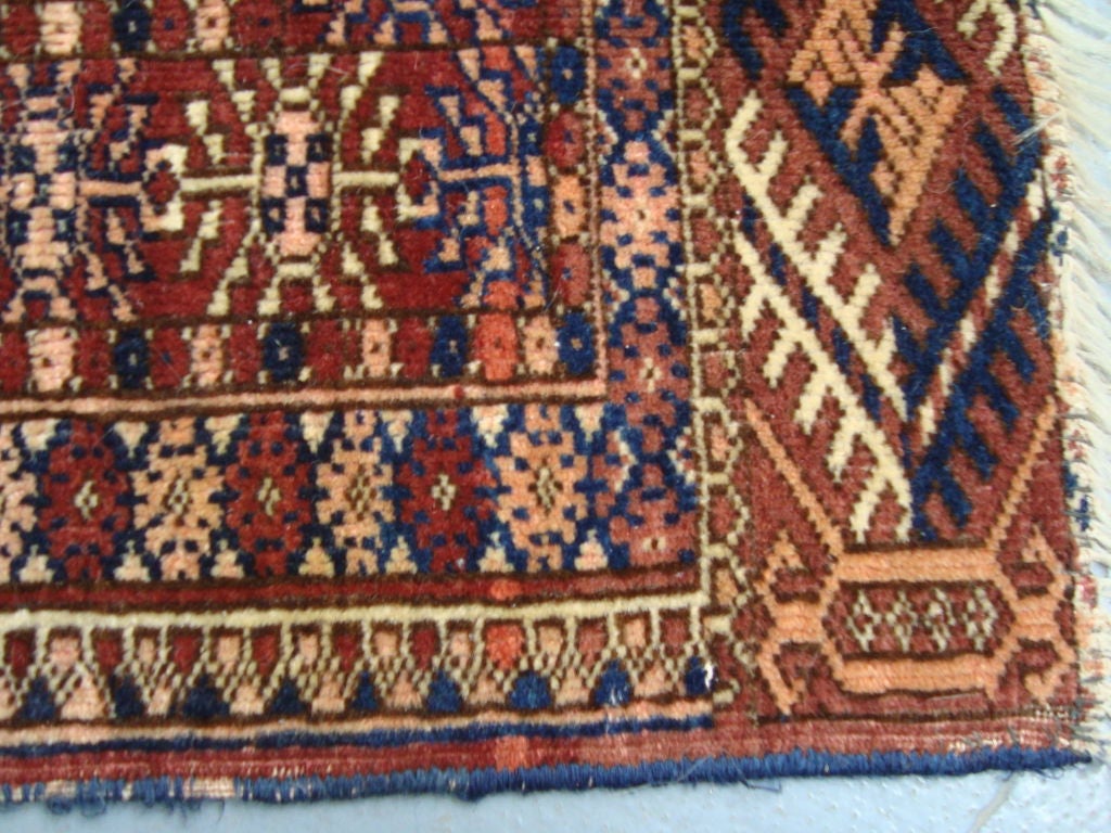 A hand-knotted throw rug with a beautiful geometric field pattern. One of two similar rugs being offered.