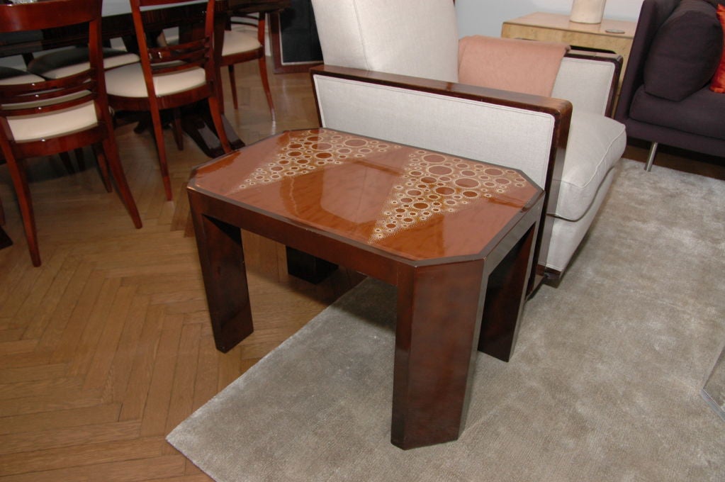A side table with heavy canted corners and inlaid on top with a beautiful Art Deco pattern in the manner of Master Jean Dunand. 

A similar smaller table made as a matched set to this one is also available.