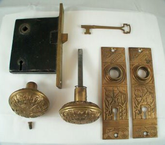 A vintage lockset / door hardware with detailed carvings in bronze, typical of Aesthetic Movement designs with stylized natural motifs and patterns.