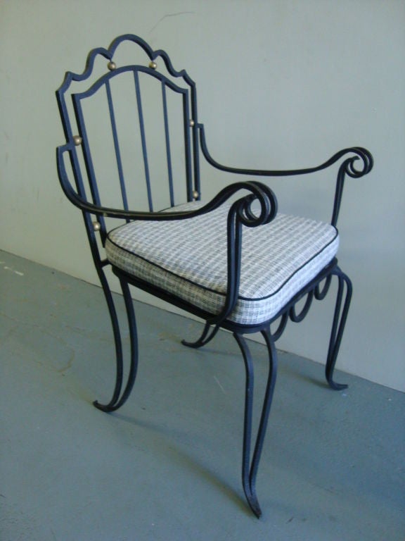 A pair of wrought iron armchairs with scroll arms and gilt accents. Each with custom (new) silk cushion. The piece is similar to examples by both Rene Prou and Arturo Pani.

Dimensions:
Seat height is 19