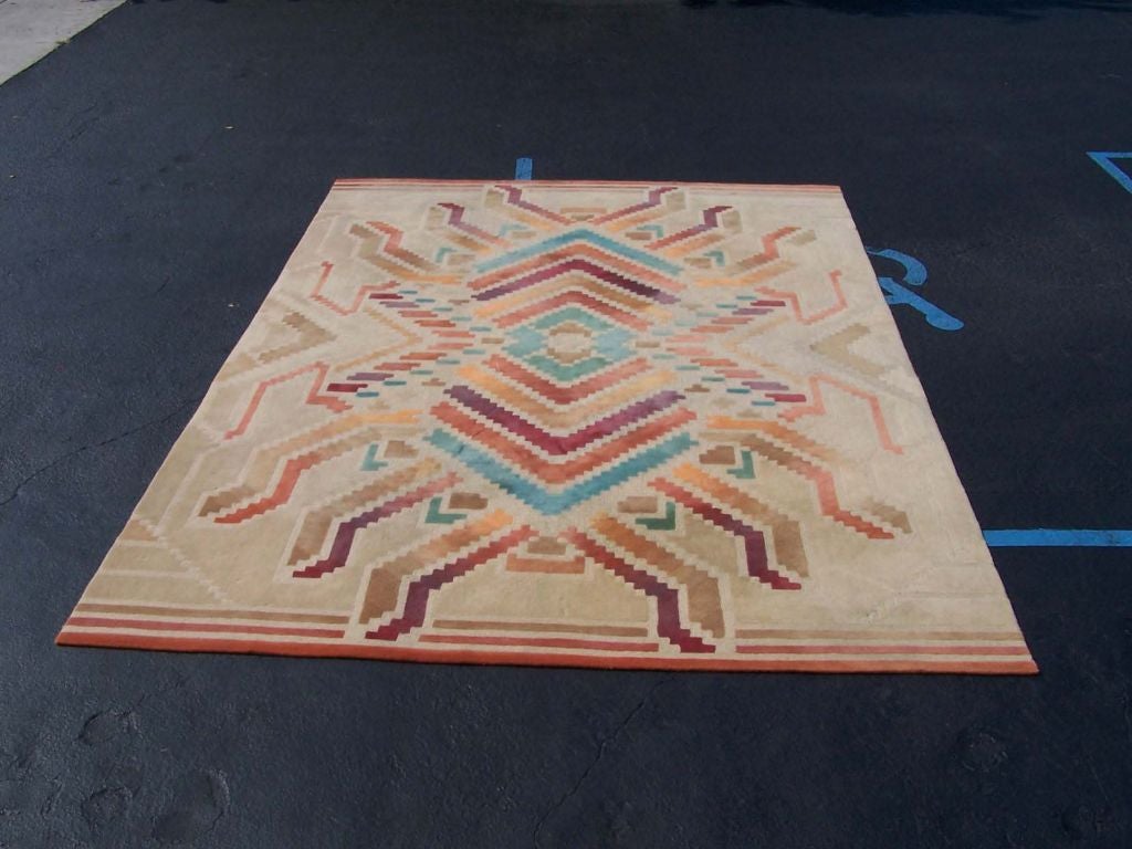 Large Edward Fields rug, signed. The rug has a tan background with various decorations in rust, camel, orange, brown, maroon, lavender, teal.***Contact/Shipping Information: AOL (American Online) users may experience difficulties sending emails to