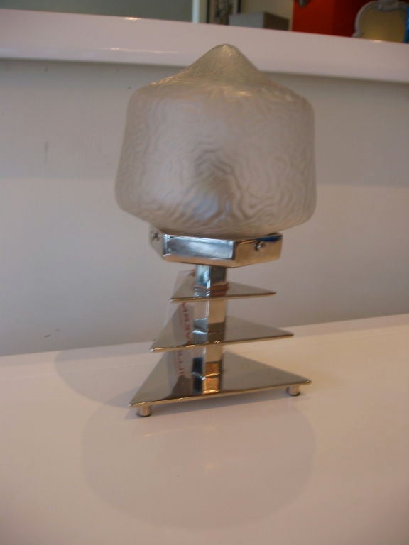 Esta original lámpara de sobremesa Art Decó francesa tiene una escultural base triangular cromada de tres niveles y una pantalla de vidrio esmerilado moldeado. Un maravilloso ejemplo del Art Déco de los años 30. Es vintage y a la vez moderno y deco.