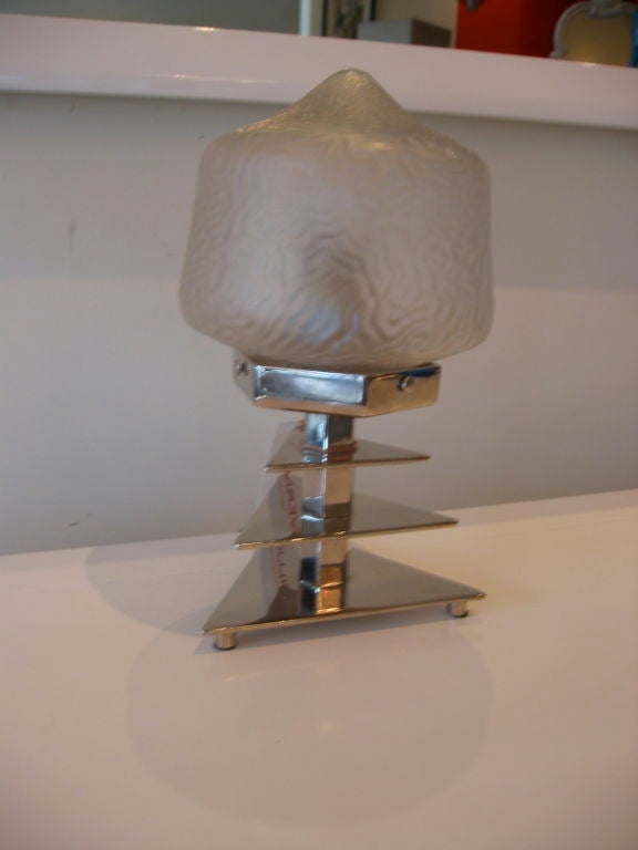 This original French Art Deco small table lamp has a sculptural three tiered triangular chrome base and a molded frosted glass shade. A wonderful example of the 1930s Art Deco. It is vintage yet modern yet deco.