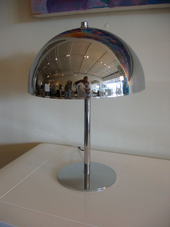 Domed top desk lamp in chrome with thin rod meeting flat round disk base.