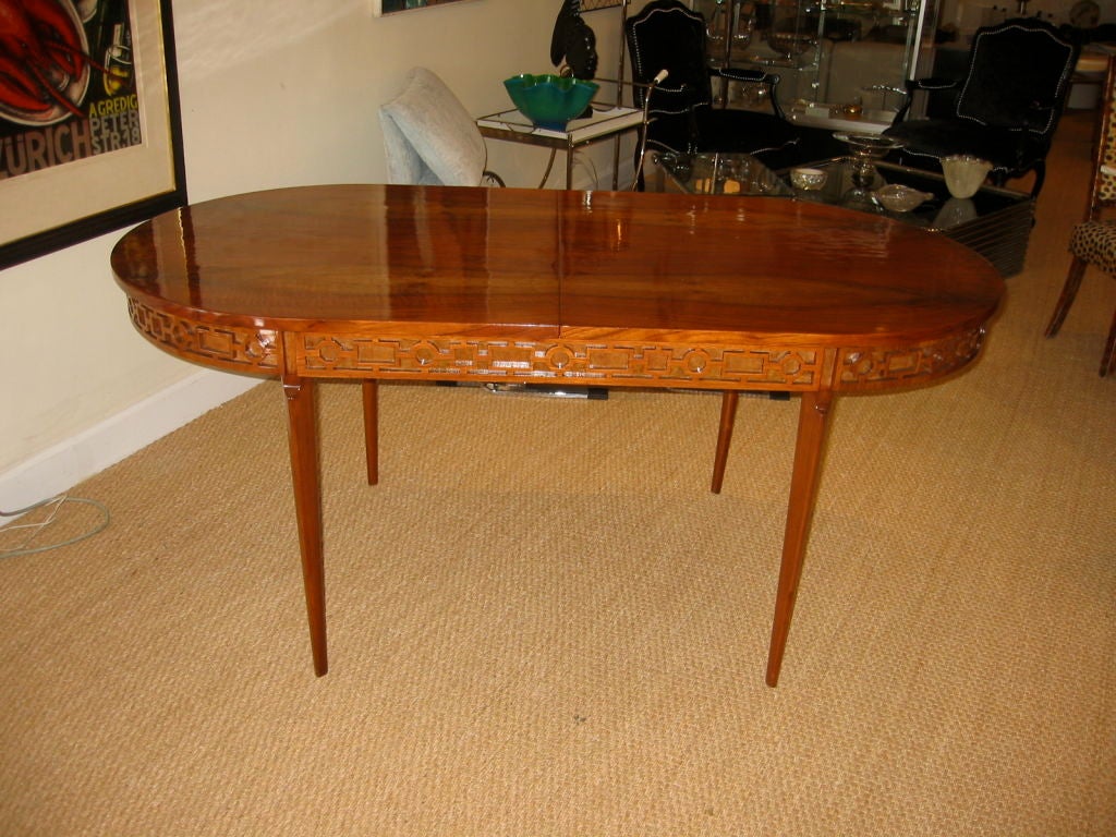 Grand oval table with finely tapered legs which are recessed from the edge of the table creating a floating effect. The table top is done in an extraordinary cathedral rosewood which is rarely used due to it's high cost although it looks