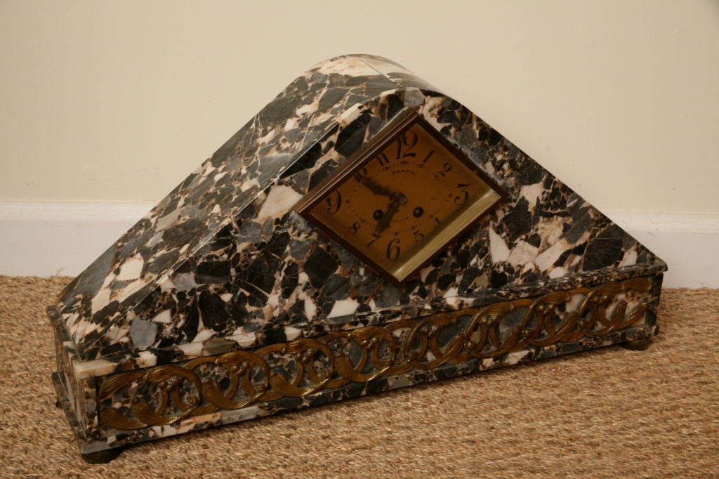 Fabulous triangular solid marble clock with brass scroll work mounted to the front bottom. Fittings are in brass and bronze with triangular clock face.