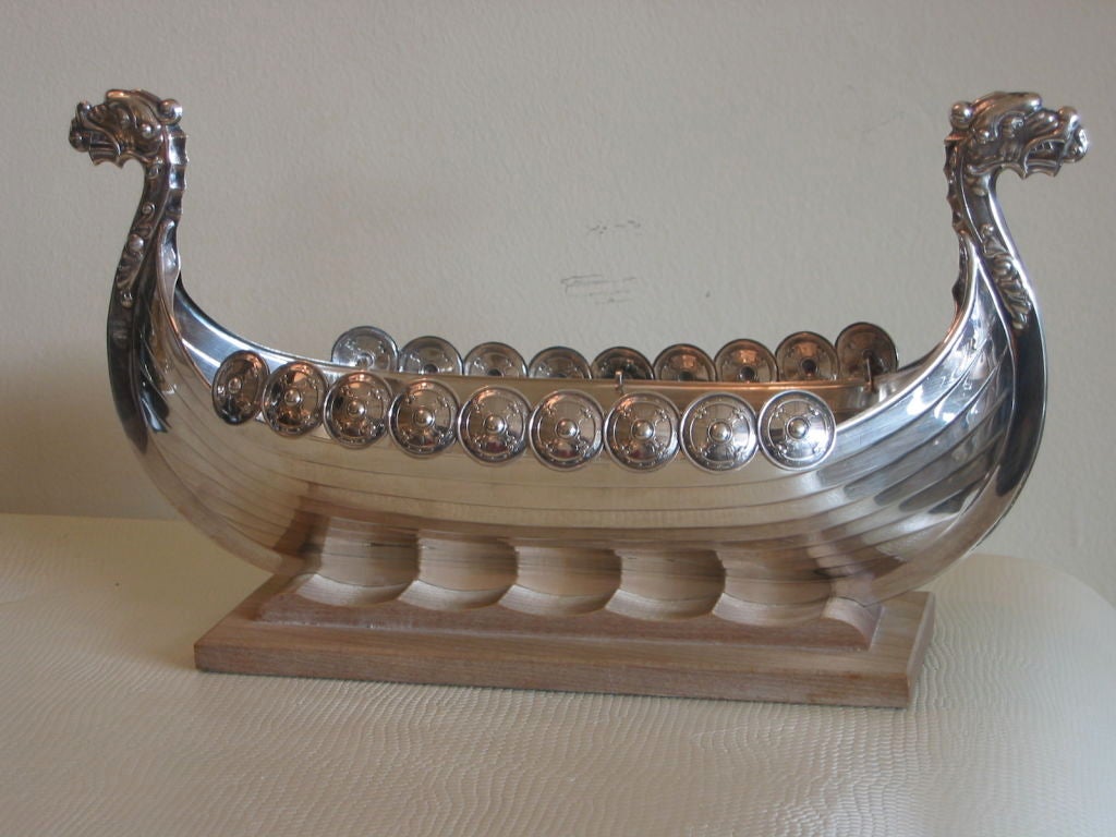 Ornately made sterling silver viking ship. Dragons on either side and removable crest strips made of multiple button size disks, also in sterling. Ship resting in wood base.This has hallmarks on the bottom. Most importantly, this was given to the