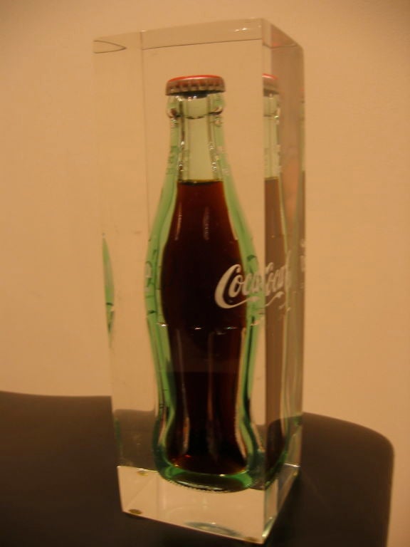 Original coca cola bottle suspended in lucite. The liquid of the coke is fluid and moving. The bottle cap gives away the age.
