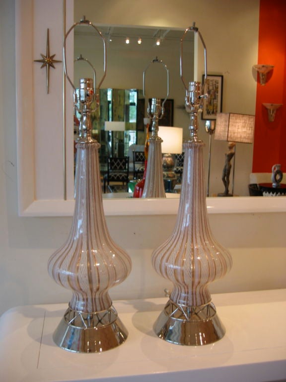Pair of genie style murano lamps with latticino work in white with copper bands and pink tones. Round nickel silver bases with nickel silver hair pin open work separating glass from base. Rewired with nickel silver fittings throughout. Very much in