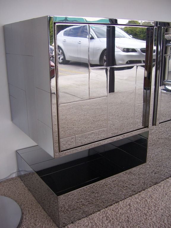 This chrome cityscape design sits atop a pedestal, features 4 doors and shelving as pictured.