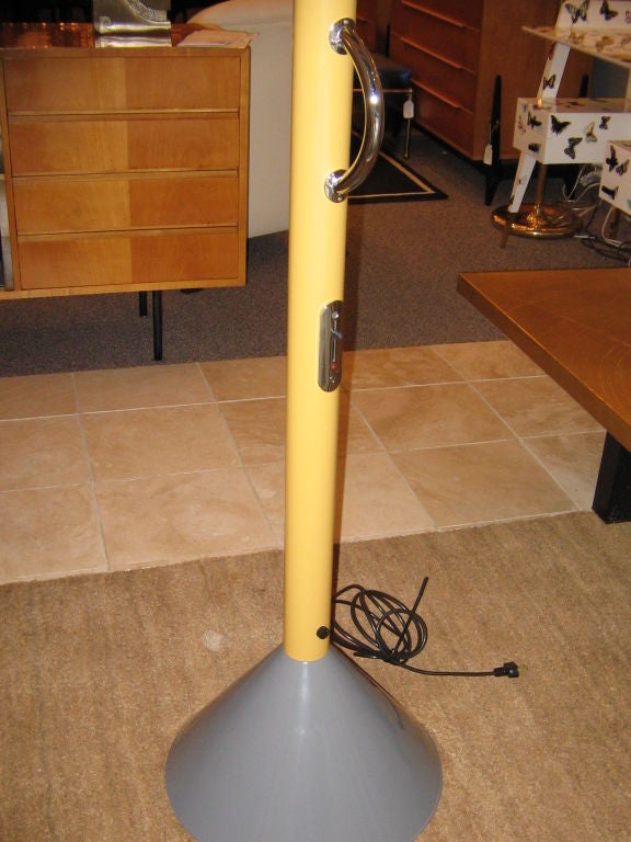 A memphis movement floorlamp, model Callimaco, featuring a large gray lacquered cone shaped base with a tubular metal body in yellow lacquer with a chrome handle and chrome switches and a small red lacquered metal cone shaped up light shade. By