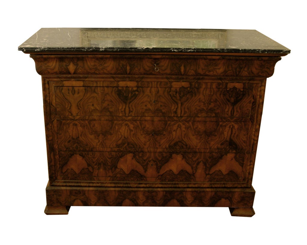 A Louis Philippe burl walnut chest with canted corners over five long drawers. Raised on molded bracket feet. Variegated black marble top can be pushed to the side to reveal a concealed hollow compartment.