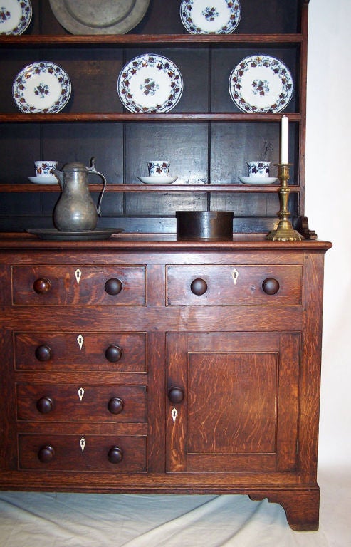 Beautifully aged oak dresser or buffet with mahogany trim, having a three shelf plate rack above three drawers over two cabinet doors and three drawers all with original wooden knobs and bone escutcheons, sitting on bracket feet. Old (possibly