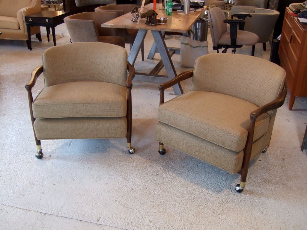 Pair of fabulous and incredibly comfortable mid century barrel chairs.  These chairs are upholstered in a textured brown fabric with undertones of green and gold.  They sit on casters with brass sabots.  The frame of the chair is stained med to dark