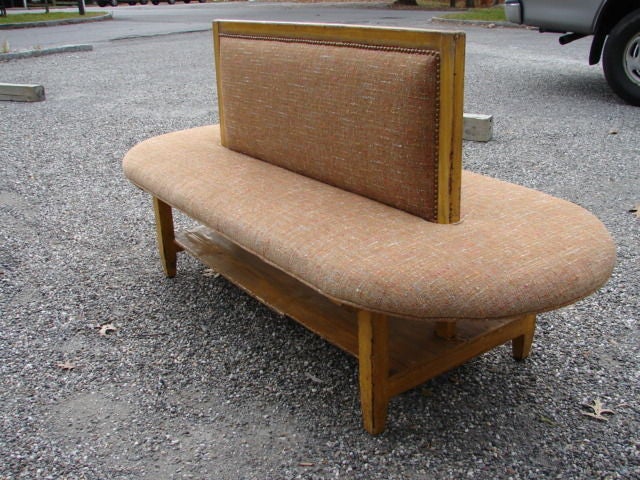 Double sided oval painted wood bench, originally a shop fitting in a shoe atelier; superb original ochre paint, with new nubby chenille upholstery and antique brass studwork. Lower shelf.