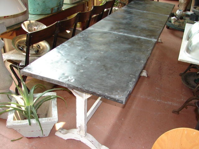 Long zinc top dining table with white painted wood base. This old zinc top has great patina. Seats 10-12.