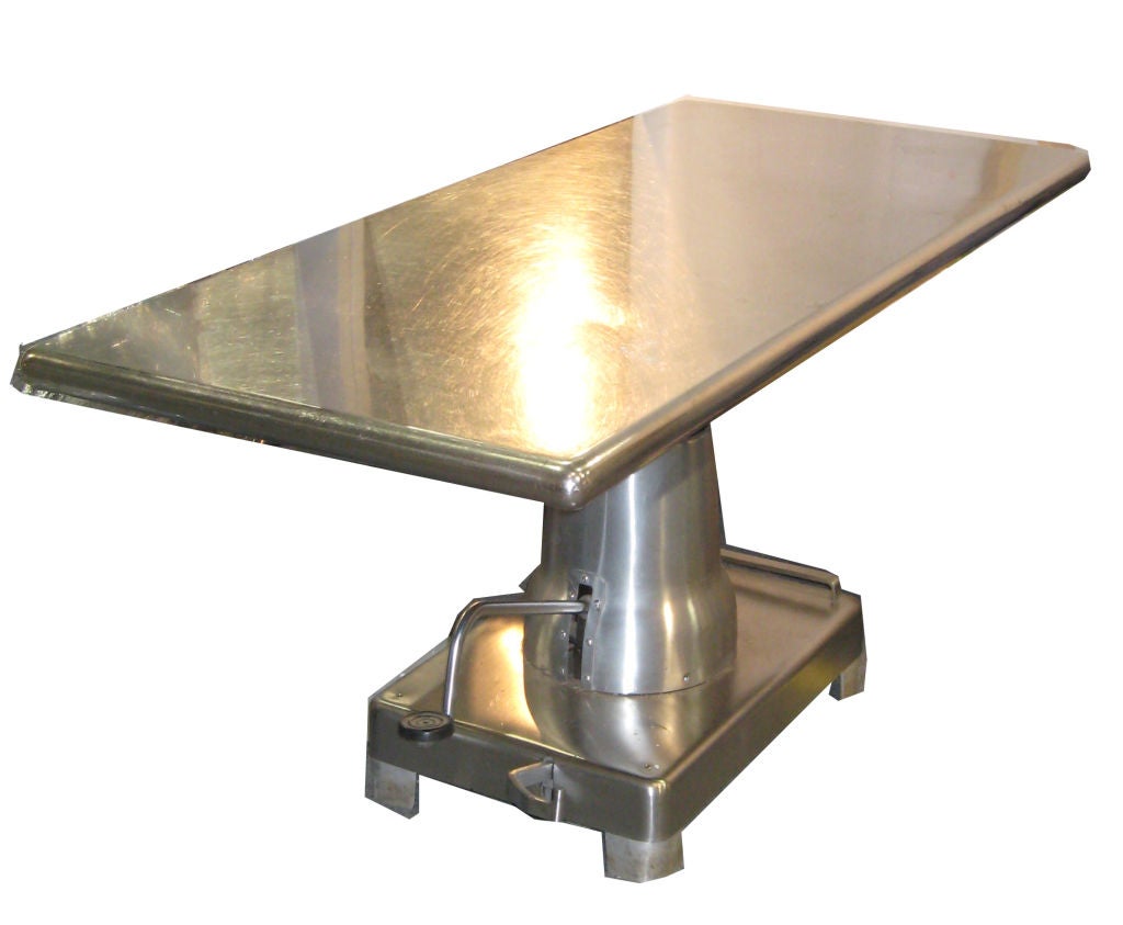 Striking table assembled with a bakery stainless steel table top and an industrial hydraulic base. Two pedals permit lifting and lowering of the top and raking of the wheels hidden under the base.