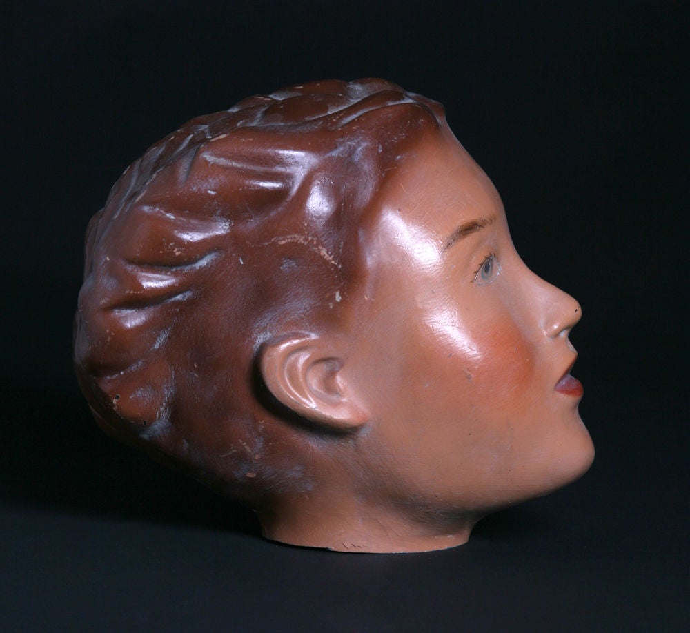 A very rare example of an American child mannequin head, c. 1930. Made originally from a mold so very breakable. Face and other features are hand-painted and in their original usage these mannequins often had wigs put on them. Given its age and