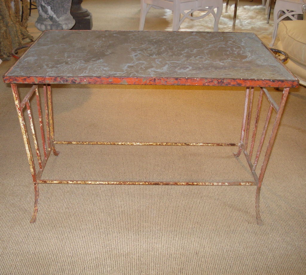 A finely proportioned hand-wrought iron table with traces of red, black and white paint and a set-in slate top