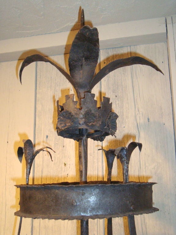 An unusual hand-wrought iron candlestand on a tripod-form base with flat diamond feet; this stand typically held spices/dried flowers (potpourri) in the trays to diffuse scent as candles burned.