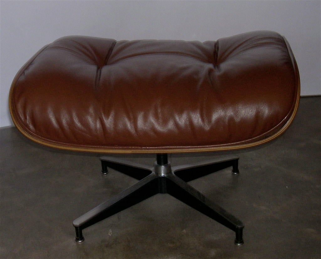 Questa sedia e questo pouf originali sono bellissimi. La calda pelle marrone terra di Siena è eccellente, così come il ricco legno di palissandro con una profonda figurazione. La combinazione funziona perfettamente per creare un raro e raffinato