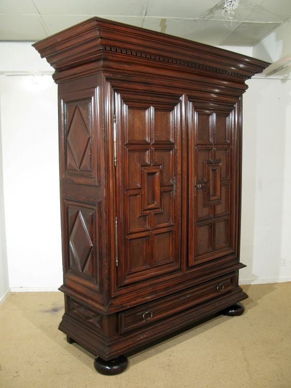 A Large Louis XIII Walnut Armoire Having A Deep Dentil Molded Cornice, Panelled Sides and Doors, a Drawer and Bun Feet.  French, Circa 1640