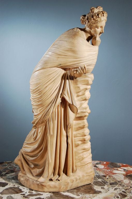 An Italian Terra Cotta Sculpture of Polyhymnia, The Greek Muse of Sacred Hymn, Poetry and Eloquence, Leaning on A Rocky Ledge. A Reproduction of a Roman Copy of a Greek Original in the Collection of the State Museum, Berlin. First Half of the 19th