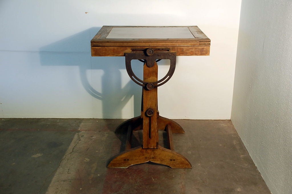 Industrial drafting table. Restored with blackened steel plate top. Great in a loft or in a kitchen as a breakfast table / bar for 2. Adjustable to an additional 8 in. tall. Top pivots for use as a drafting / writing table. Also good as a sculptural